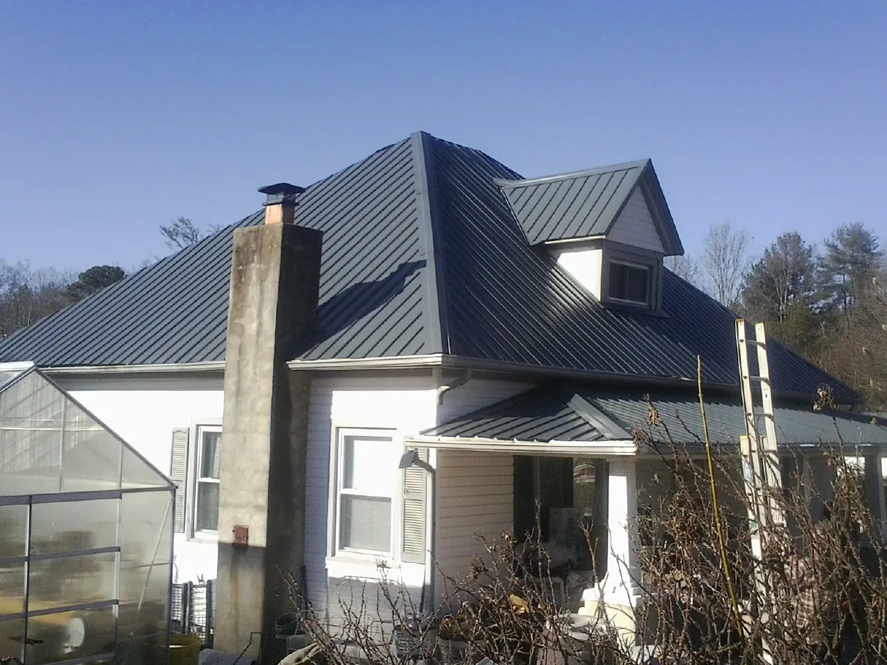 Dark blue standing seam metal roof on a white farmhouse with dormer — Slate & Tile Roof Repair by Roofing Brothers in Placerville