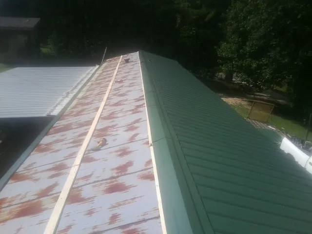 Old rusted panels beside newly installed green metal roofing — Wind Damage Roof Repair by Roofing Brothers in Placerville