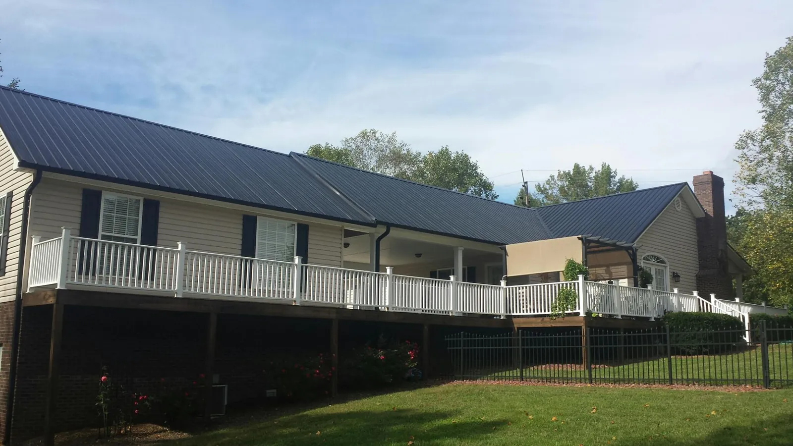 Black metal roof above a long white railed deck on a hillside home in Placerville