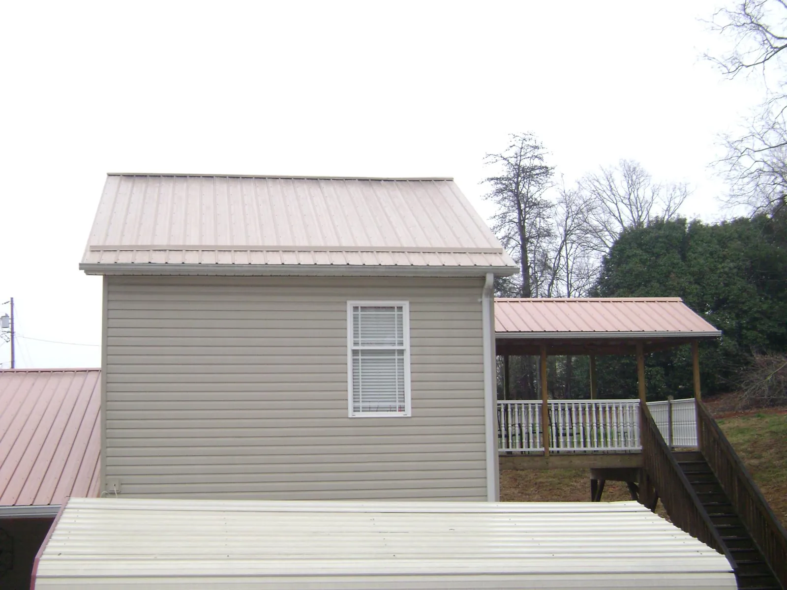 Tan metal roofs on a two story addition and attached porch, from a Roof Replacement job in Placerville