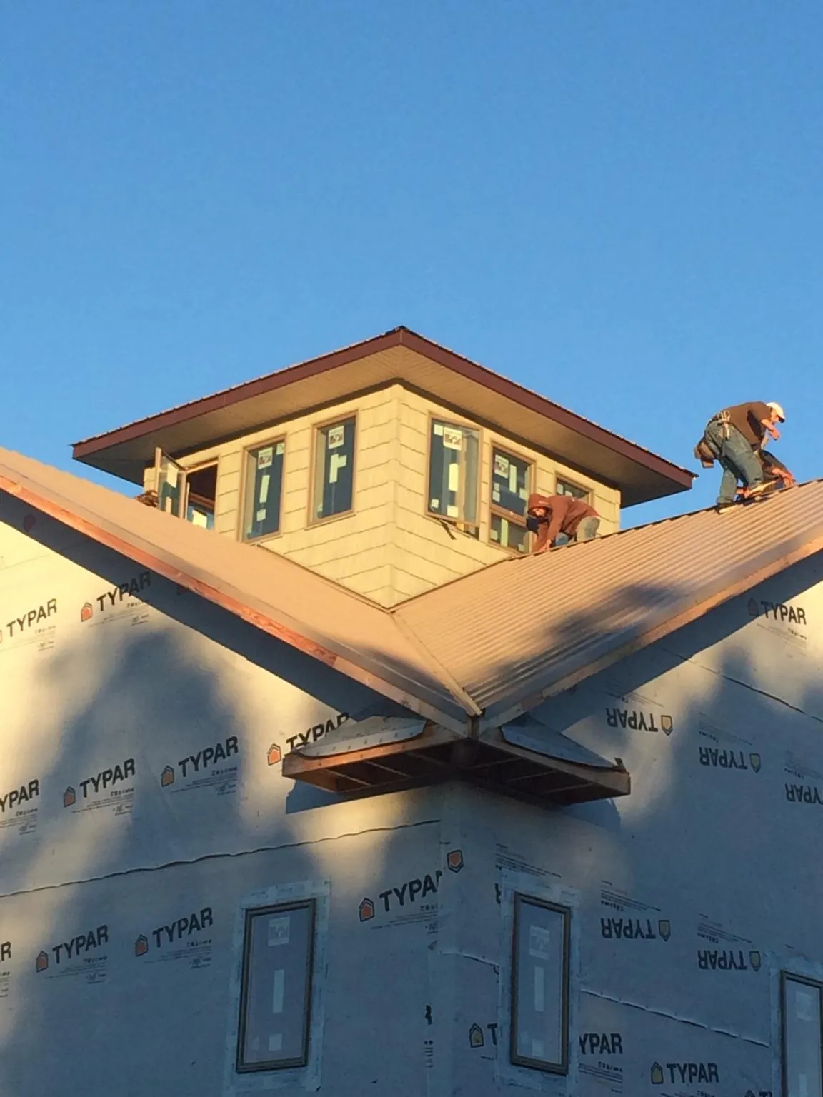 Roofers working around a rooftop cupola on a new metal roof at sunset — Roof Waterproofing in Placerville by Roofing Brothers